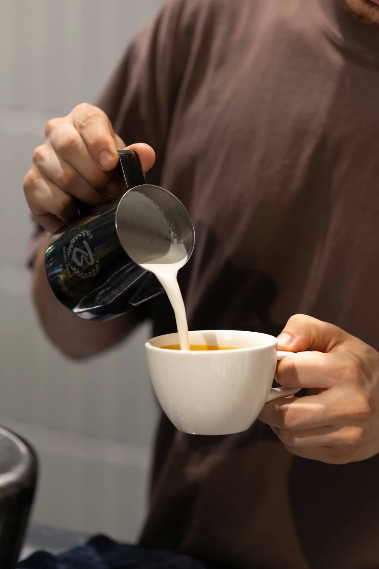 Baristro — barista turnând lapte în cappuccino